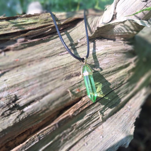 Vivid green quartz crystal point necklace displayed on weathered wood